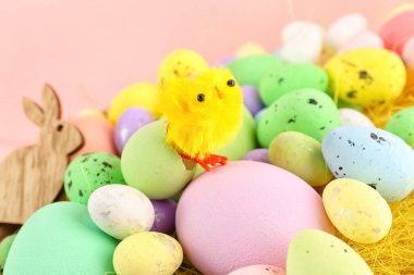 Painted Easter eggs and toy chicks on color background, closeup