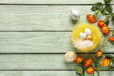 Composition with nest of Easter eggs and flowers on color wooden background