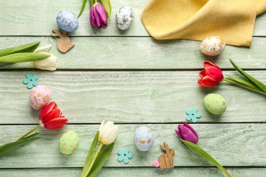 Frame made of Easter eggs, beautiful tulip flowers and decor on color wooden background