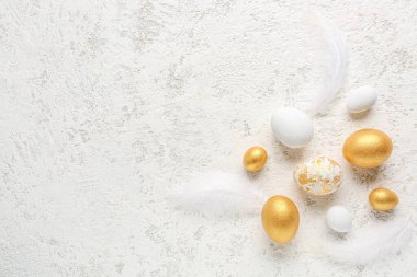 Composition with beautiful Easter eggs and feathers on light background