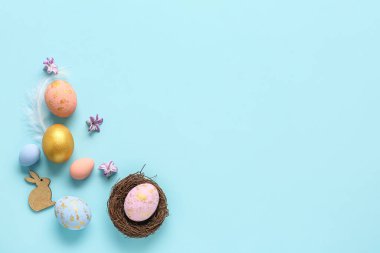 Composition with nest, Easter eggs, decor and flowers on color background