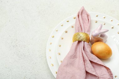 Stylish table setting with Easter egg and ceramic bunny on light background, closeup