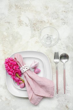 Table setting with Easter eggs, hyacinth flowers and bunny on white grunge background