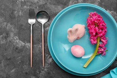 Table setting with Easter egg, hyacinth flowers and bunny on grey grunge background