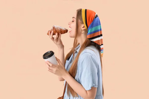 Mladá Žena Šálkem Kávy Jíst Croissant Béžovém Pozadí — Stock fotografie