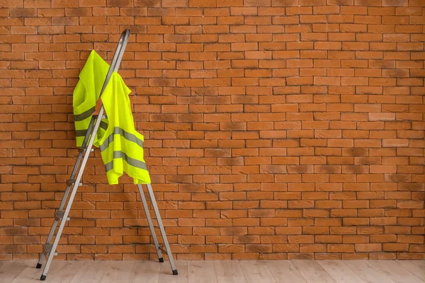 Safety vest on stepladder near brick wall