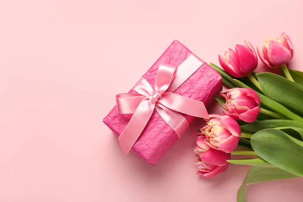 Gift box and beautiful tulip flowers on pink background. Hello spring