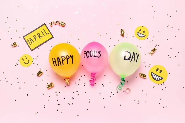 Composition with balloons, party decor and sequins on pink background. April Fool\'s Day celebration