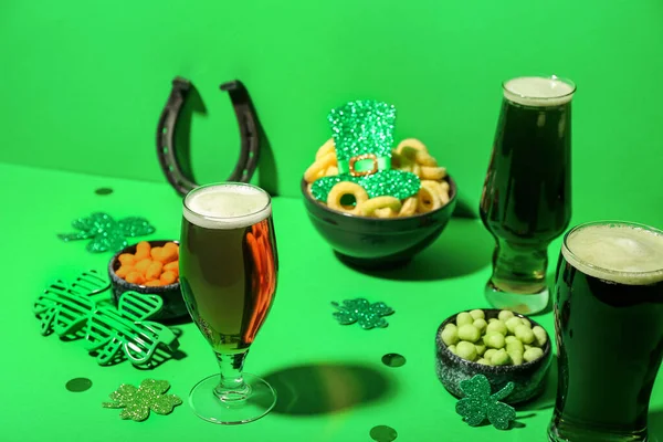 Glasses of beer, snacks and decor on green background. St. Patrick\'s Day celebration