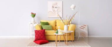 Interior of living room with Easter decor, yellow sofa and tables