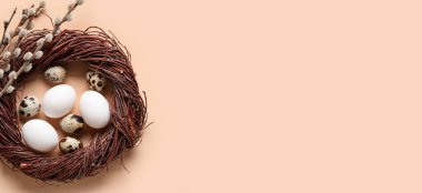 Easter wreath, eggs and pussy willow branches on beige background with space for text