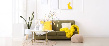 Interior of light living room with Easter decor, green sofa and table