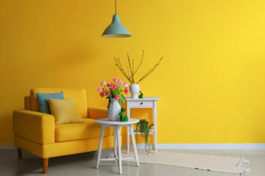 Interior of living room decorated for Easter celebration with armchair and tulips in vase