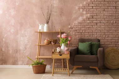 Vase with tulips, Easter bunny and cake on end table in living room near brick wall