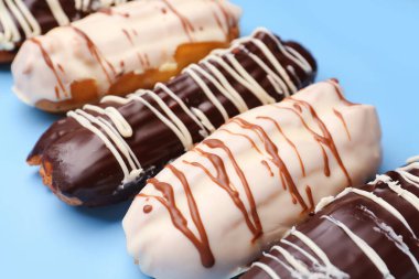 Many delicious eclairs on blue background