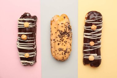 Tasty glazed eclairs on colorful background