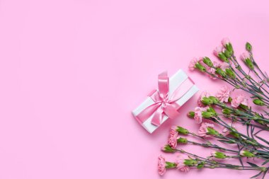Gift box and beautiful carnation flowers on pink background. Women's Day celebration