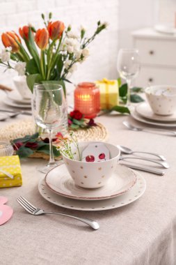 Table setting for International Women's Day celebration and vase with flowers in dining room