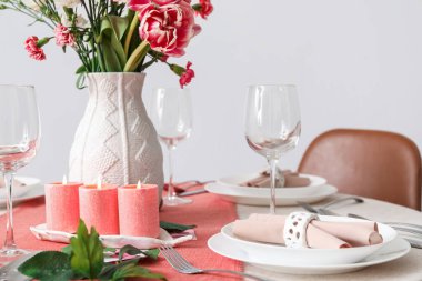 Beautiful setting for International Women's Day celebration with burning candles, glasses and flowers on table