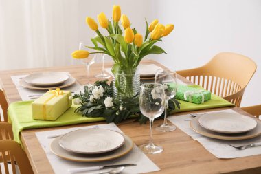 Table setting for International Women's Day celebration with gifts and tulip flowers in light room