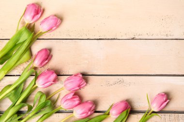 Frame made of beautiful tulip flowers on beige wooden background