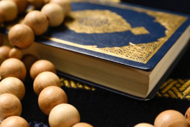 Koran with prayer beads for Ramadan on mat, closeup