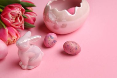 Easter bunny, tulip flowers and painted eggs on pink background