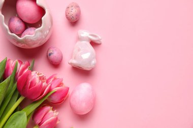 Easter bunny, tulip flowers and painted eggs on pink background