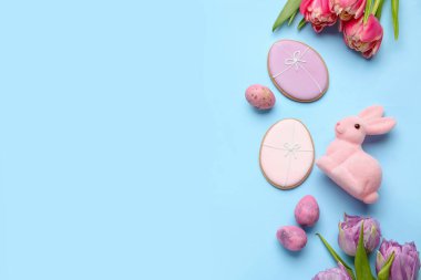 Easter bunny, tulip flowers, cookies and painted eggs on blue background