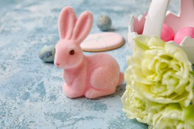 Easter bunny, tulip flowers and painted eggs on blue grunge background