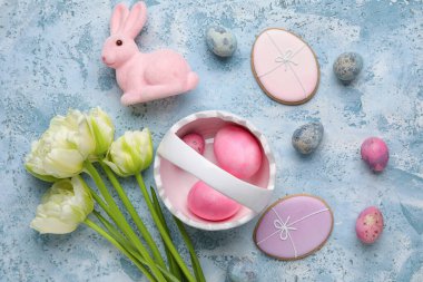Easter bunny, cookies, tulip flowers and painted eggs on blue grunge background