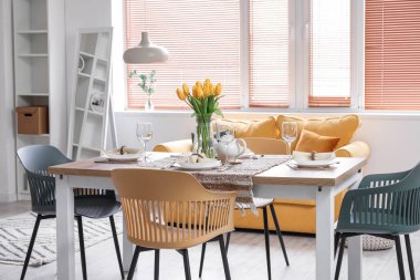 Table setting for International Women's Day celebration with tulip flowers in interior of room