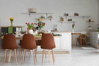 Beautiful table setting for International Women's Day celebration with different flowers in interior of light room