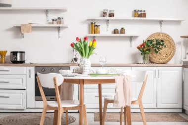 Table setting for International Women's Day celebration with tulip flowers and teapot in interior of room