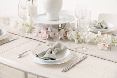 Beautiful table setting for International Women's Day celebration with orchid flowers in interior of light room