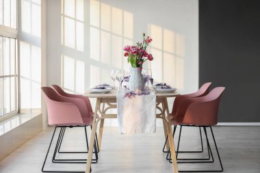 Beautiful table setting for International Women's Day celebration with carnation flowers in light room near window