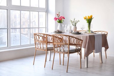 Beautiful table setting for International Women's Day celebration with flowers in light room near window