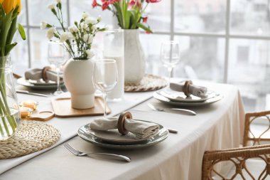 Beautiful table setting for International Women's Day celebration with flowers in light room near window