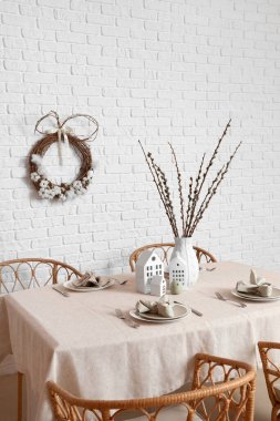 Dining table with willow branches and candle holders in room