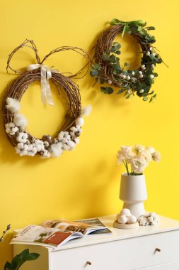 Easter wreaths hanging on yellow wall in room