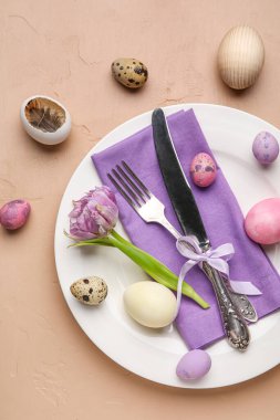 Table serving with Easter eggs and tulip flower on brown grunge background