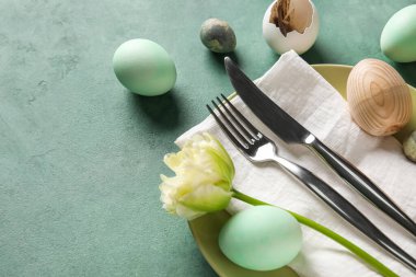 Table serving with Easter eggs and tulip flower on green grunge background