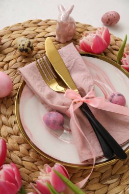 Table serving with Easter eggs, bunny and tulip flowers on white background