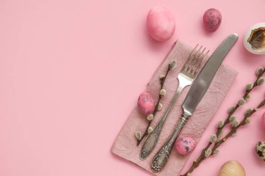 Table serving with Easter eggs and pussy willow branches on pink background