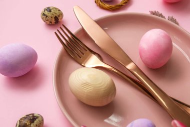 Table serving with Easter eggs on pink background, closeup