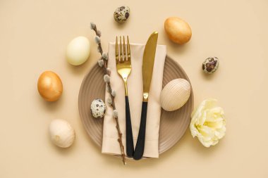 Table serving with Easter eggs, pussy willow branch and tulip flower on beige background