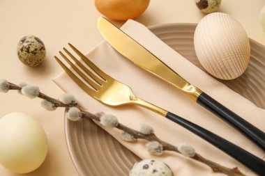 Table serving with Easter eggs and pussy willow branch on beige background