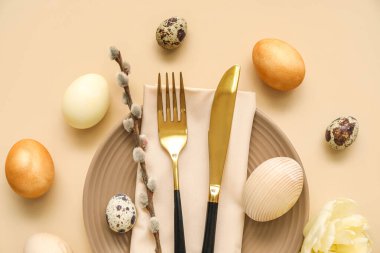 Table serving with Easter eggs and pussy willow branch on beige background