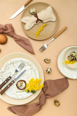 Stylish table setting with Easter eggs and mimosa flowers on color background