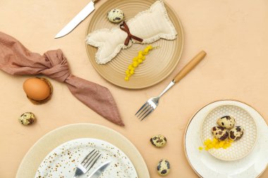 Stylish table setting with Easter eggs and mimosa flowers on color background